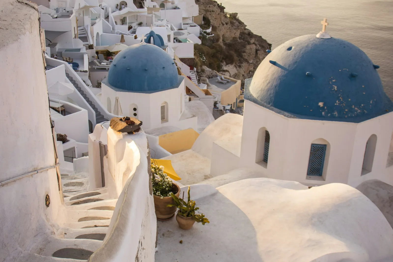 Whitewashed houses and blue-domed churches step down the cliffs of Santorini towards the sea.